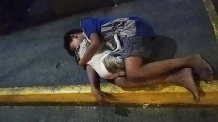 Niño sin hogar abraza a su perrito para no pasar frío