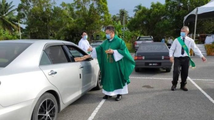 Ofician misa en el estacionamiento de una iglesia