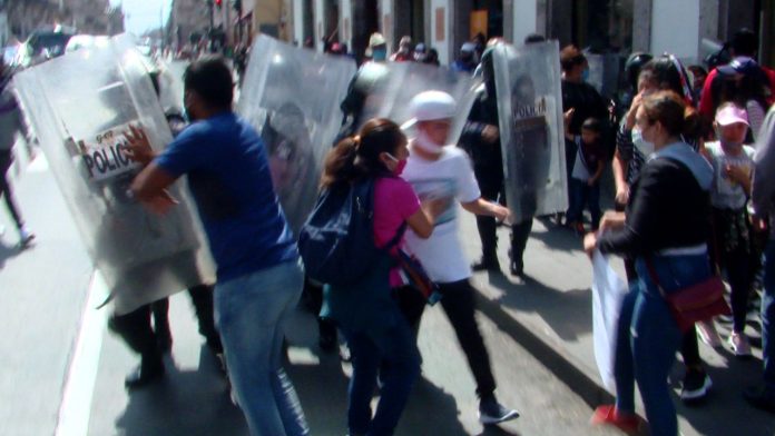 Entre empujones, granaderos quitan a rechazador en manifestación; estos se resisten.