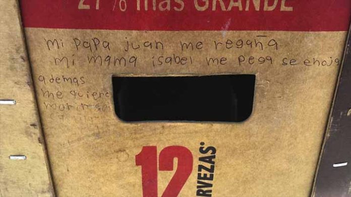 Niña escribe mensaje pidiendo ayuda en un cartón de cerveza
