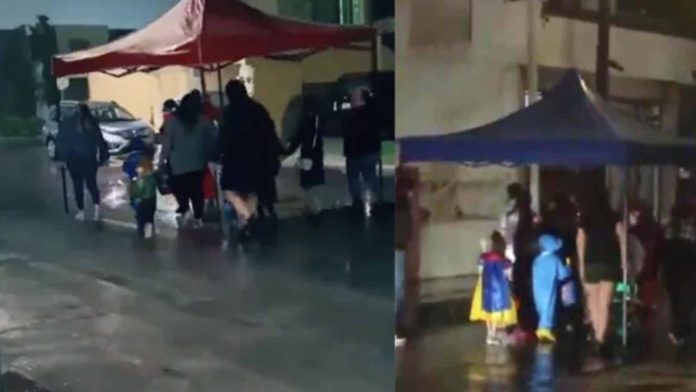 Mamás cargan una carpa para que sus hijos pidan ‘calaverita’ pese a la lluvia