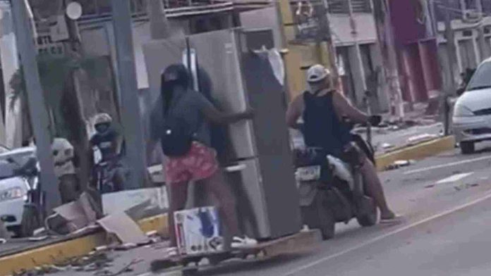 Saqueadores se llevan refrigerador en una moto tras el paso de huracán Otis