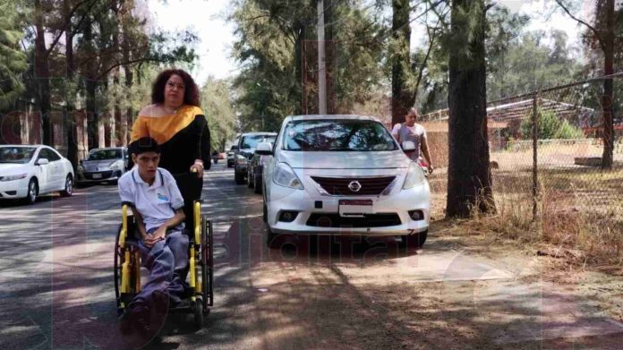 Vehículos invaden banqueta del CREE: padres llevan a sus hijos a media calle